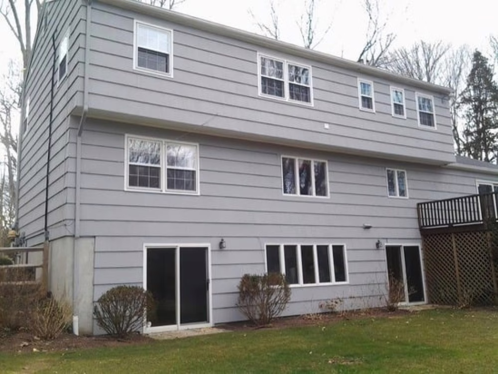 Rear view of a multi-story home before renovation, showing old panel siding soon to be replaced with Cedar Shake Siding.